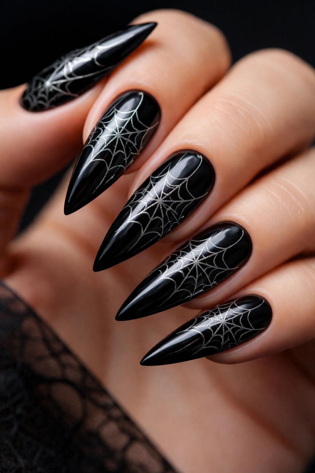 Close-up of black stiletto nails with silver spiderweb design
