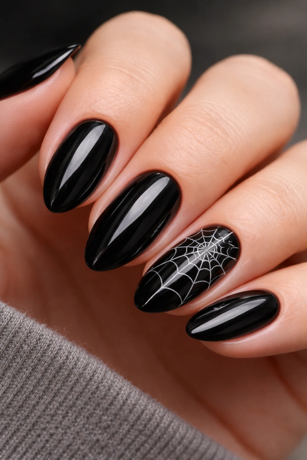 Close-up of short almond nails with a white spiderweb accent nail