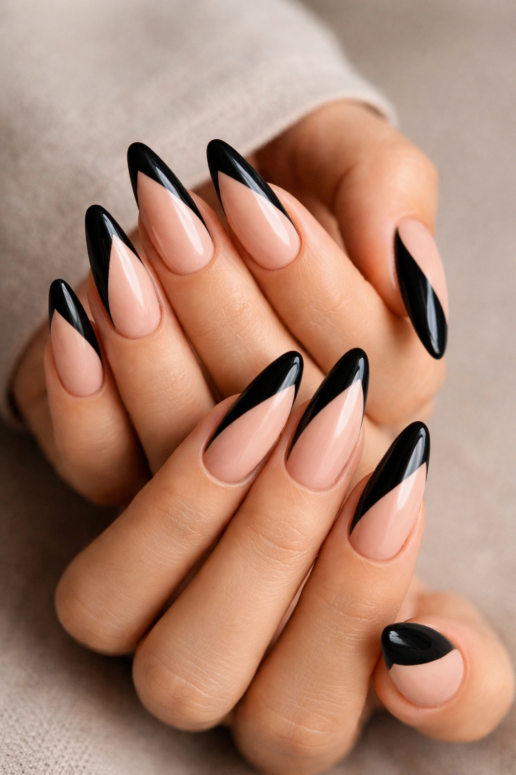 Close-up of long almond nails with a diagonal black split French on nude base.