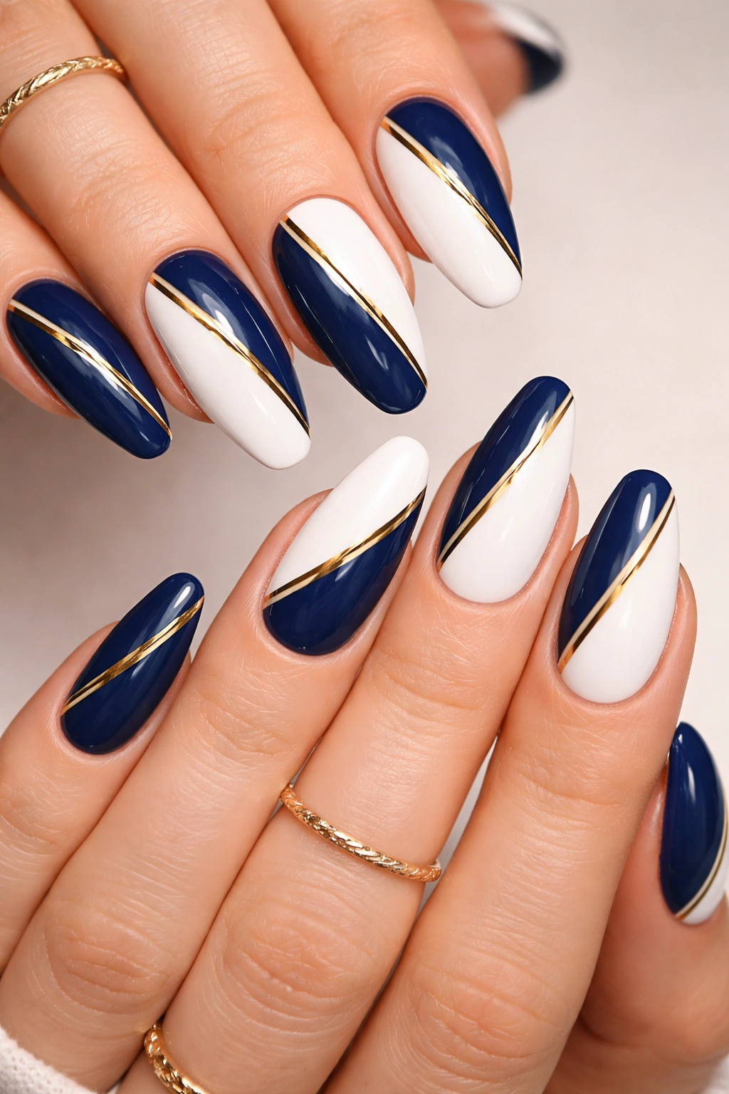 Close-up of split-design nails with diagonal color halves and gold stripe