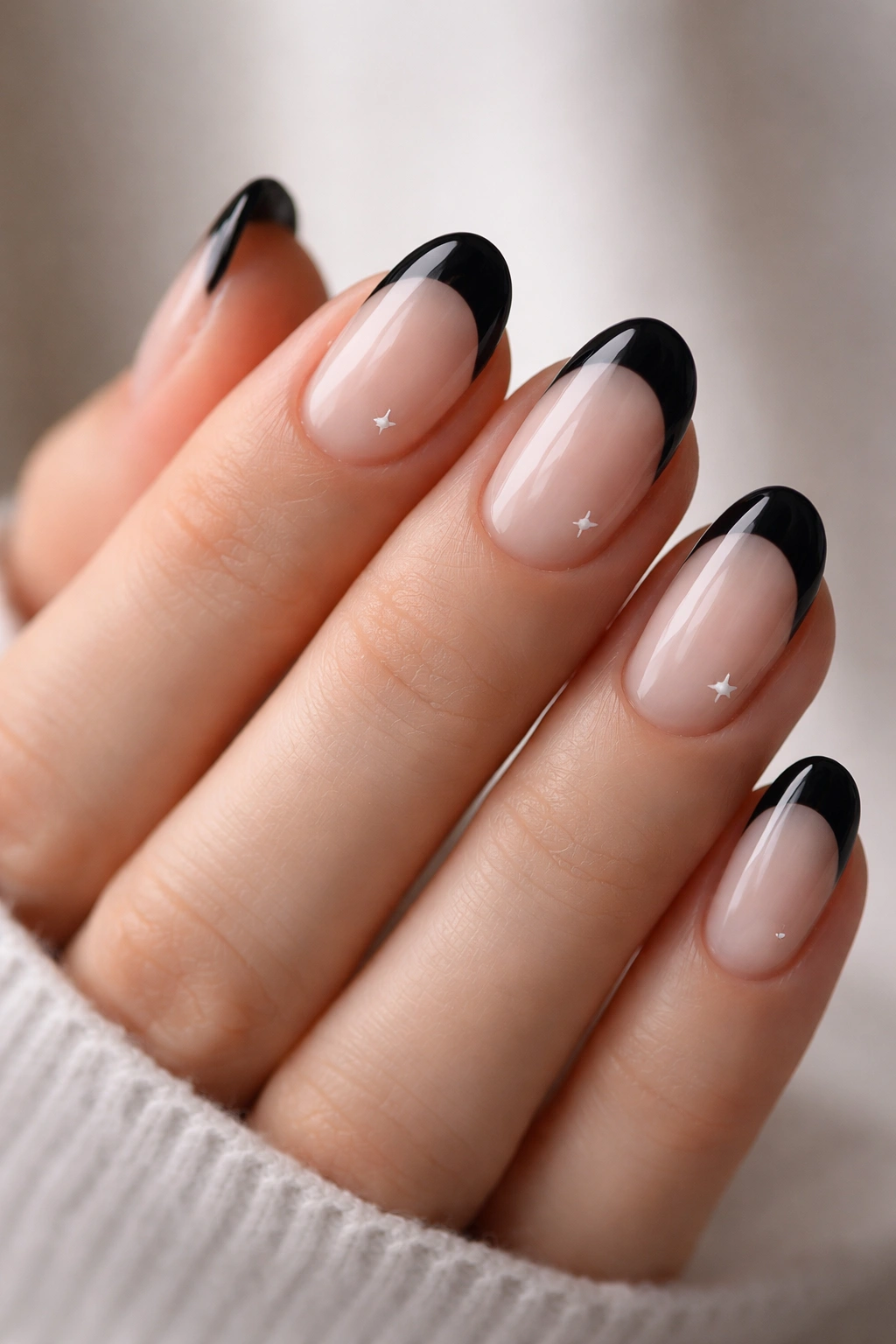 Close-up of short oval nails with black tips and tiny star details.