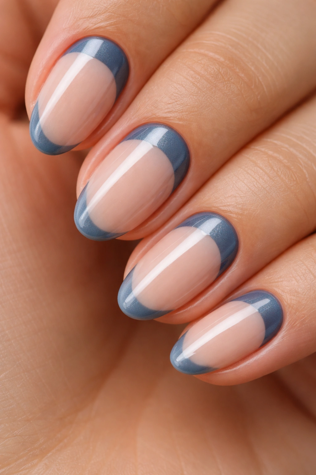 Close-up of a short almond nail with steel blue reverse French tip at the cuticle.