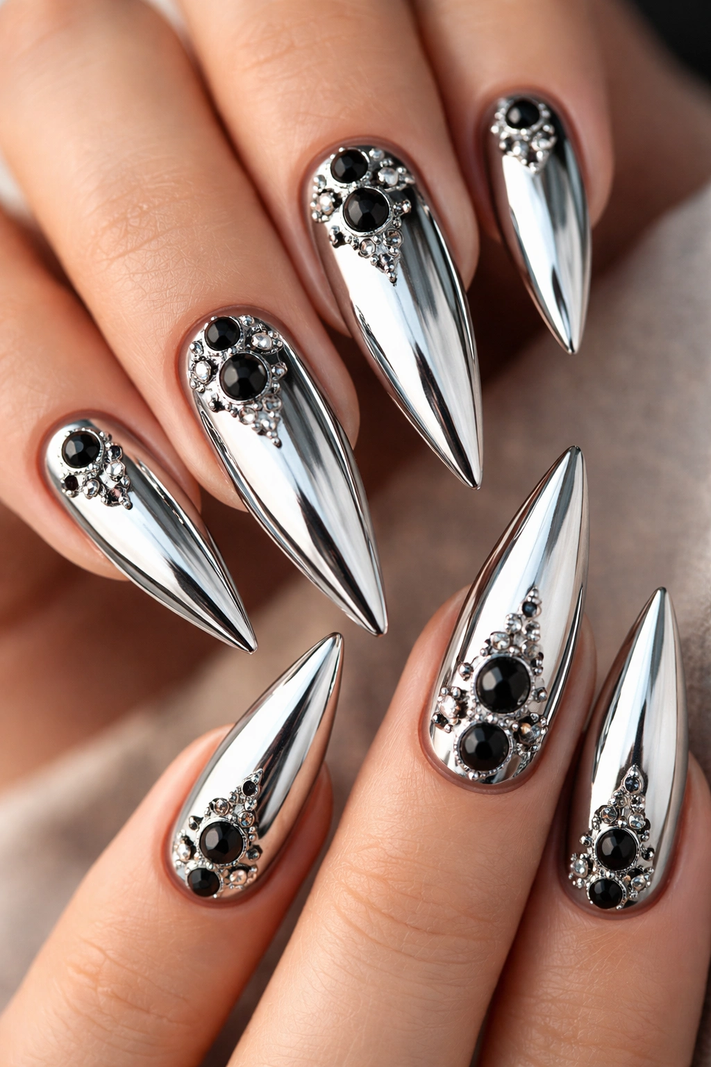 Close-up of chrome stiletto nails with black onyx charm accents