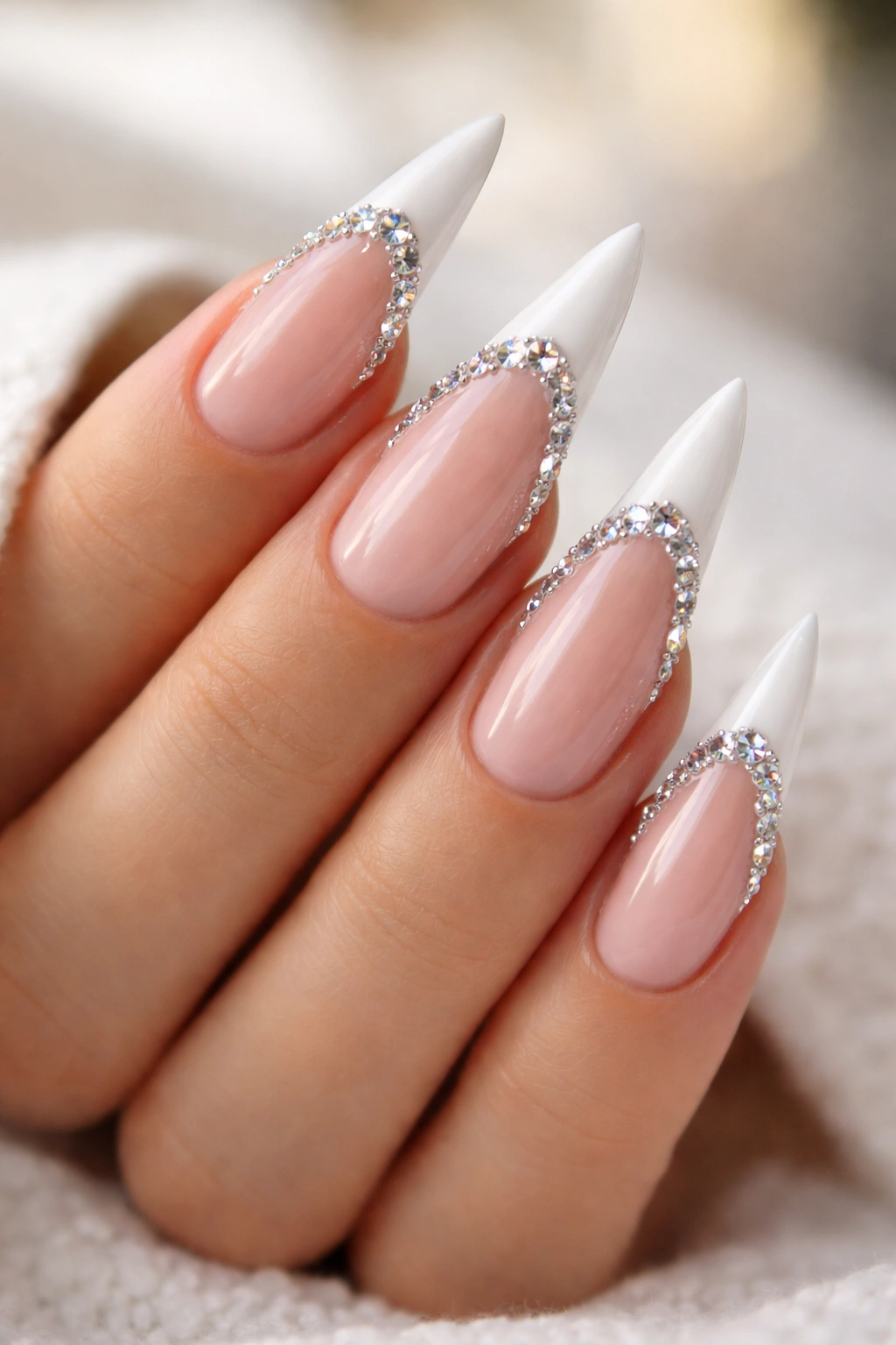 Close-up of nude stiletto nails with rhinestones along the French tip edge