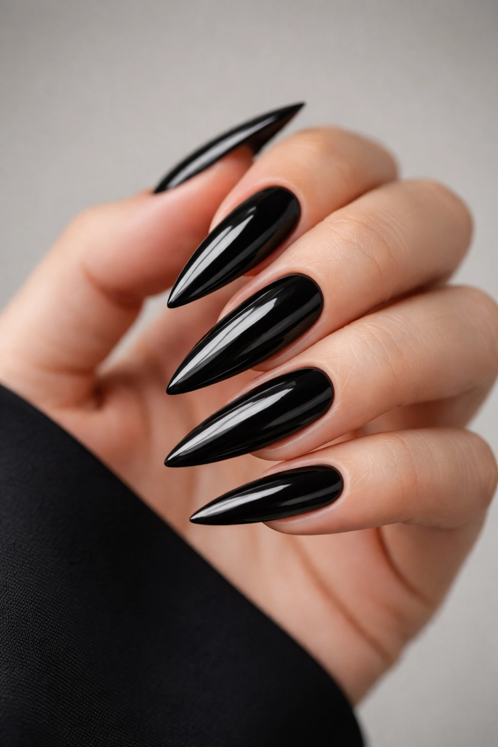 Close-up of classic high-gloss black stiletto nails with mirror finish