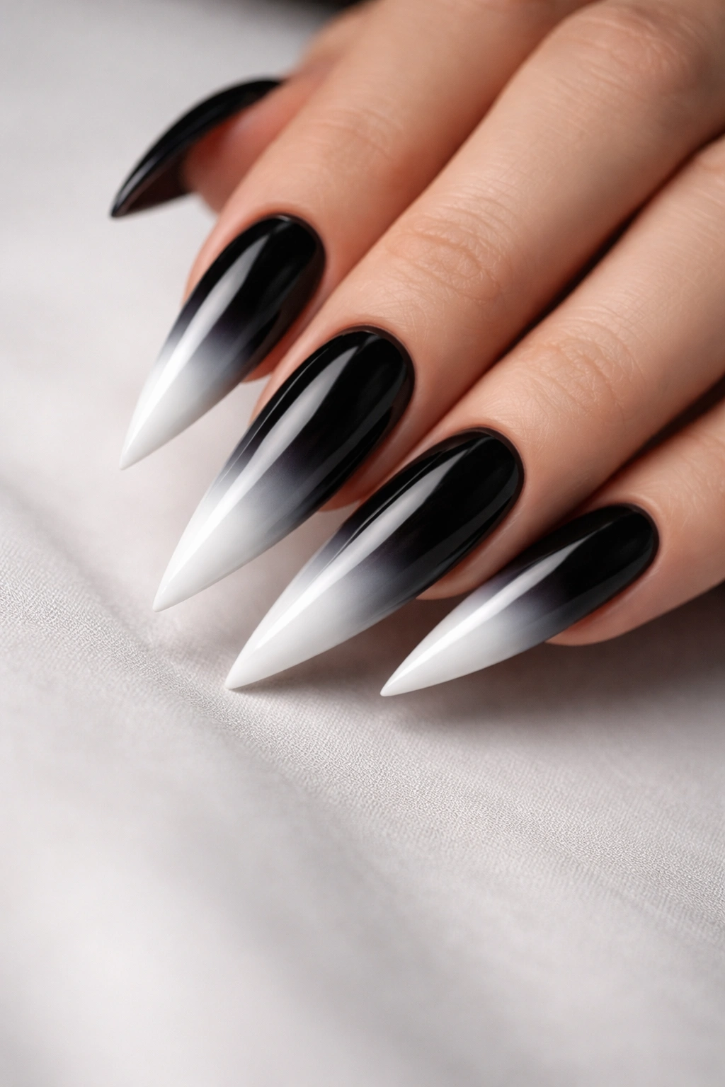 Close-up of black-to-white ombre stiletto nails with sharp tips
