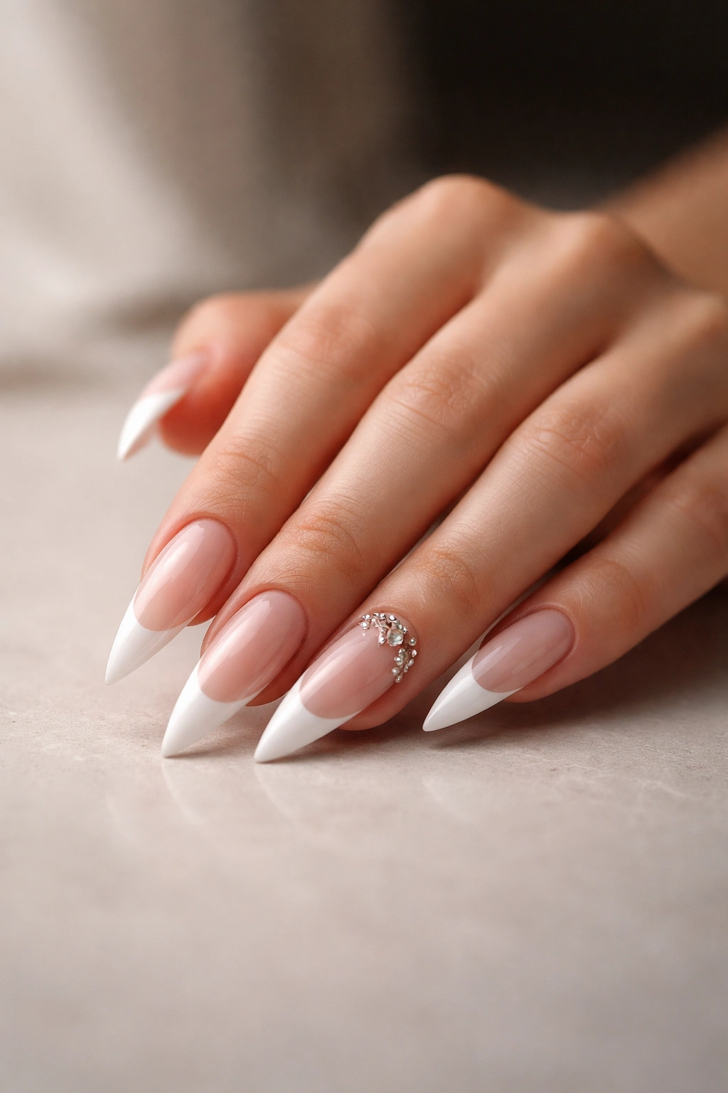 Close-up of a hand with stiletto nails and white French tips in soft studio lighting