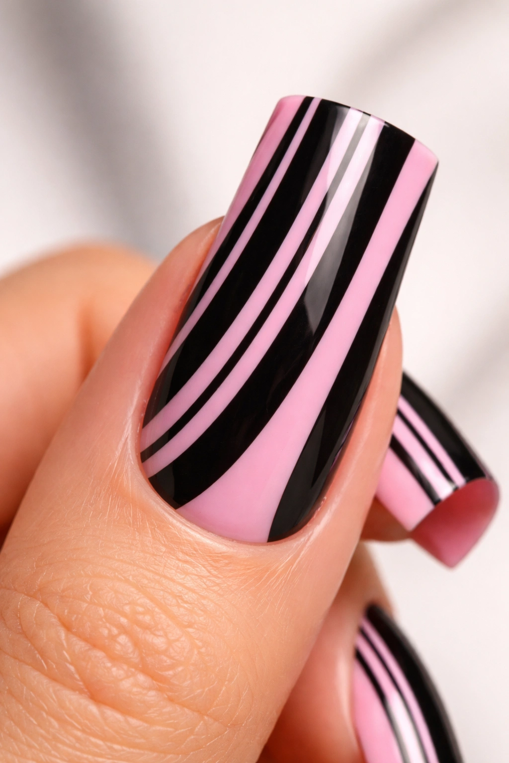 Close-up of a duck nail with striped design of varied pink and black stripe widths.