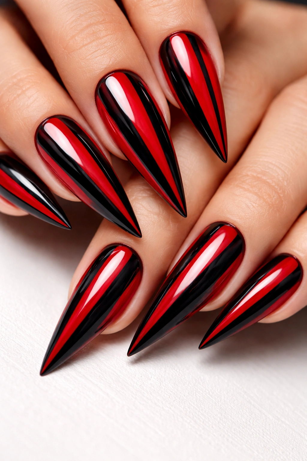 Close-up of red and black striped stiletto nails