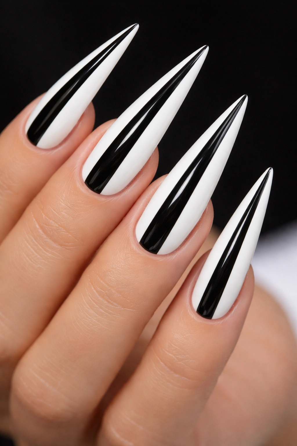 Close-up of stiletto nails with bold vertical black and white stripes