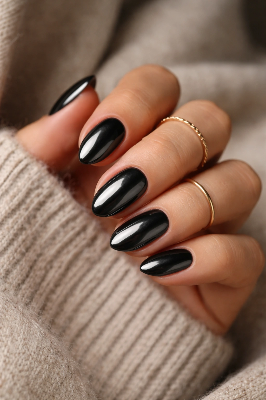 Close-up of styled black chrome almond nails against textured backdrop