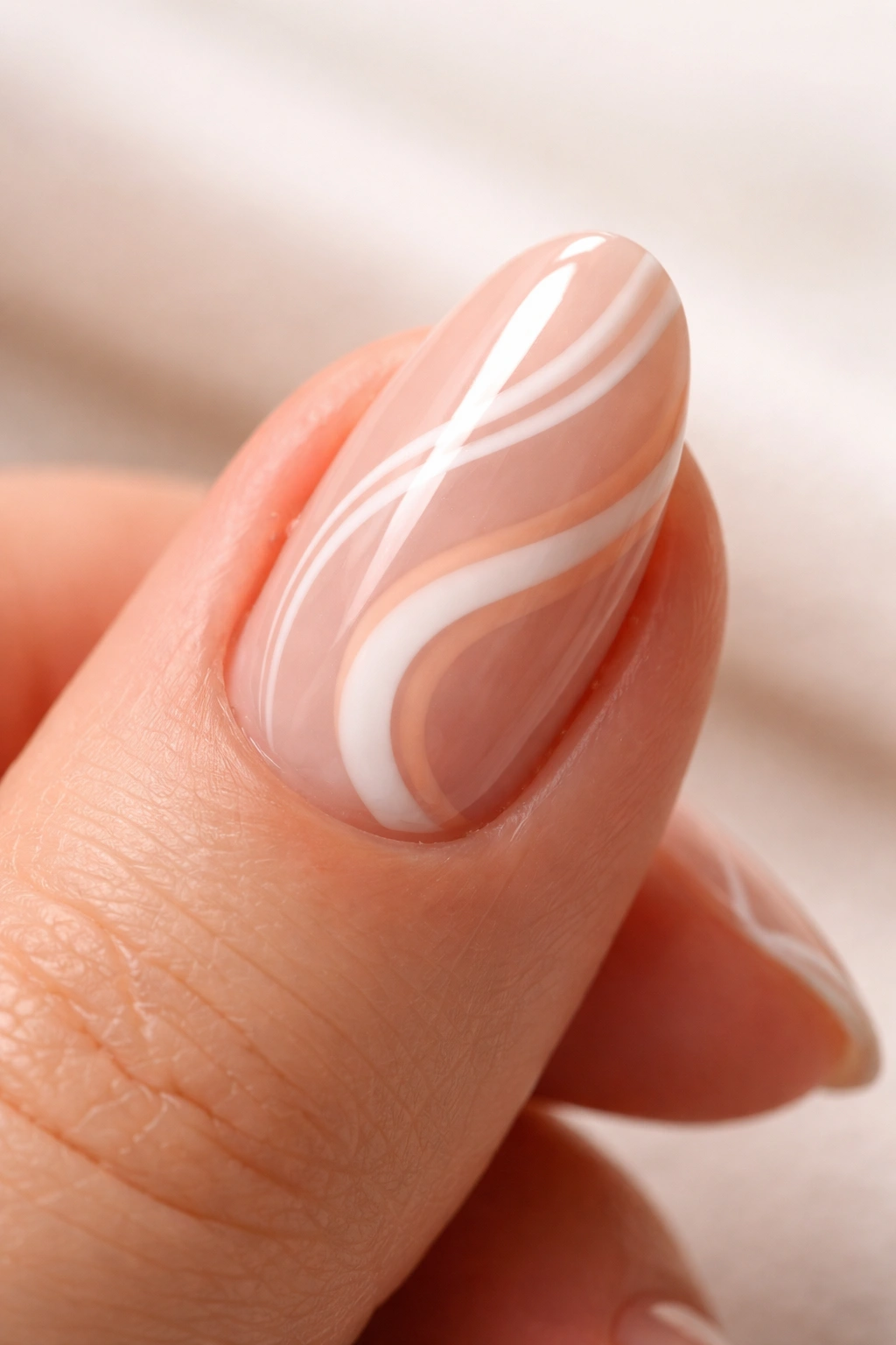 Close-up of a short almond nail with a glossy swirl design