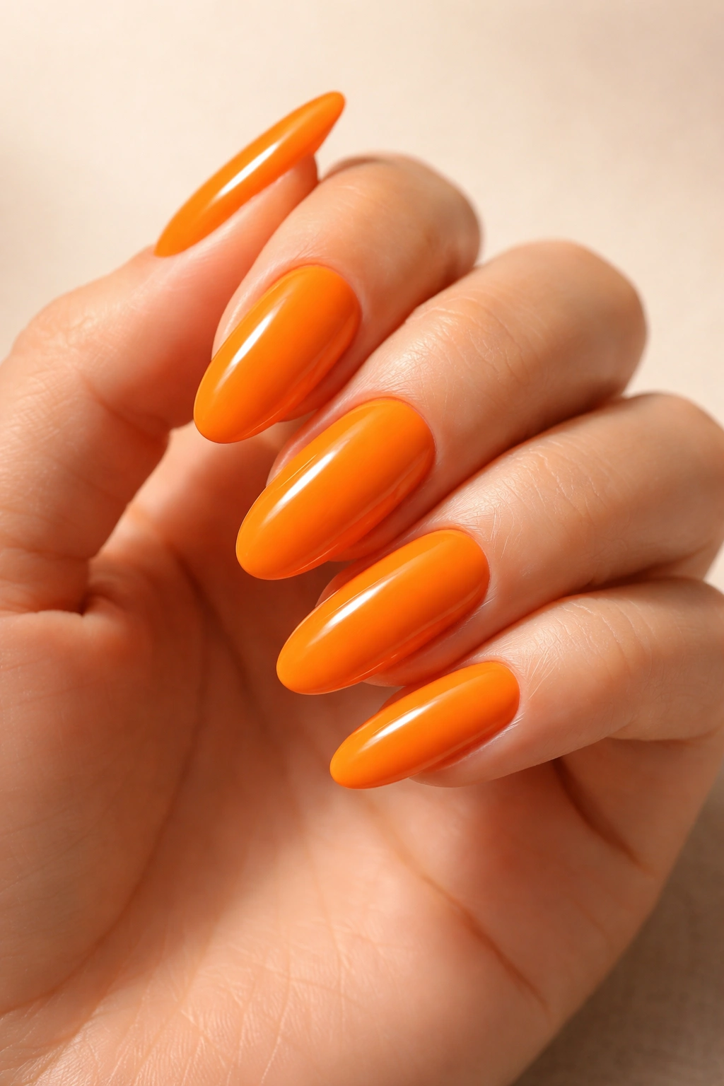 Close-up of long oval tangerine orange nails with glossy finish