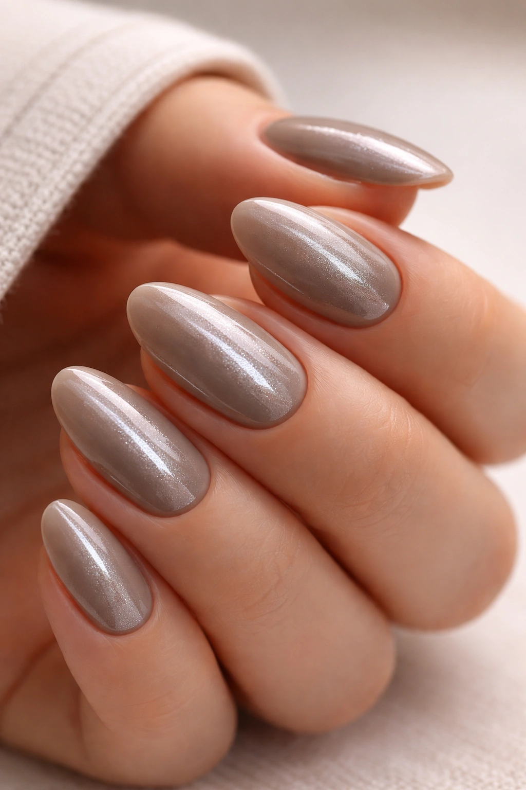 Close-up of short almond nails in taupe chrome with cat-eye shine