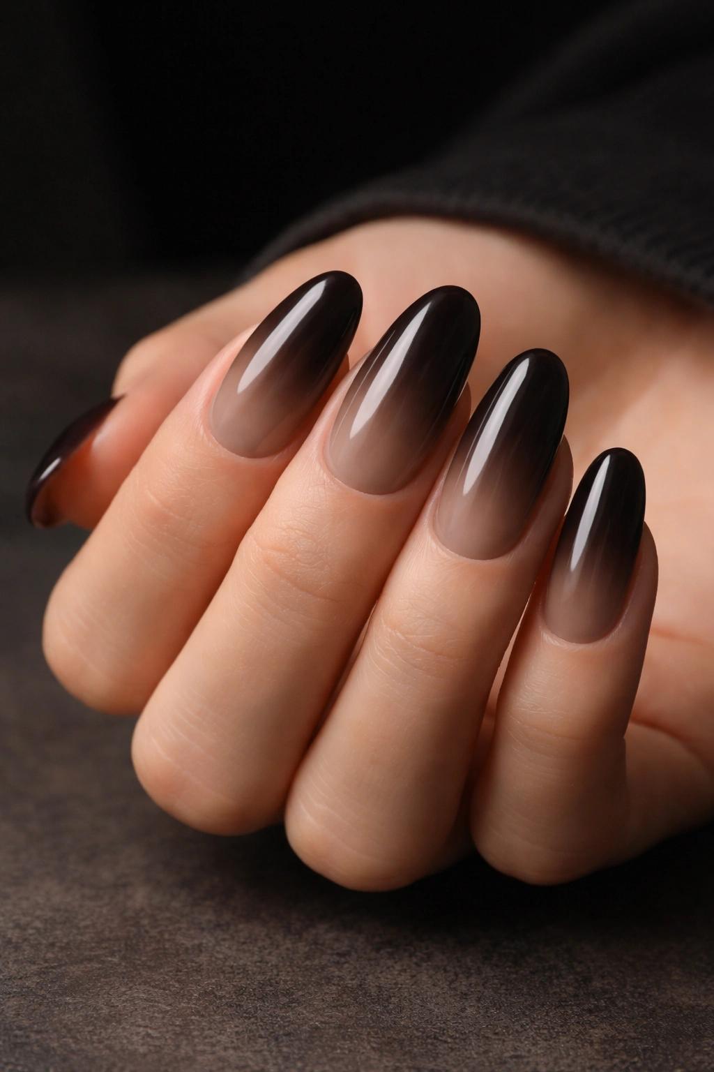Long oval nails with smoky taupe fading to deep espresso in a moody setting