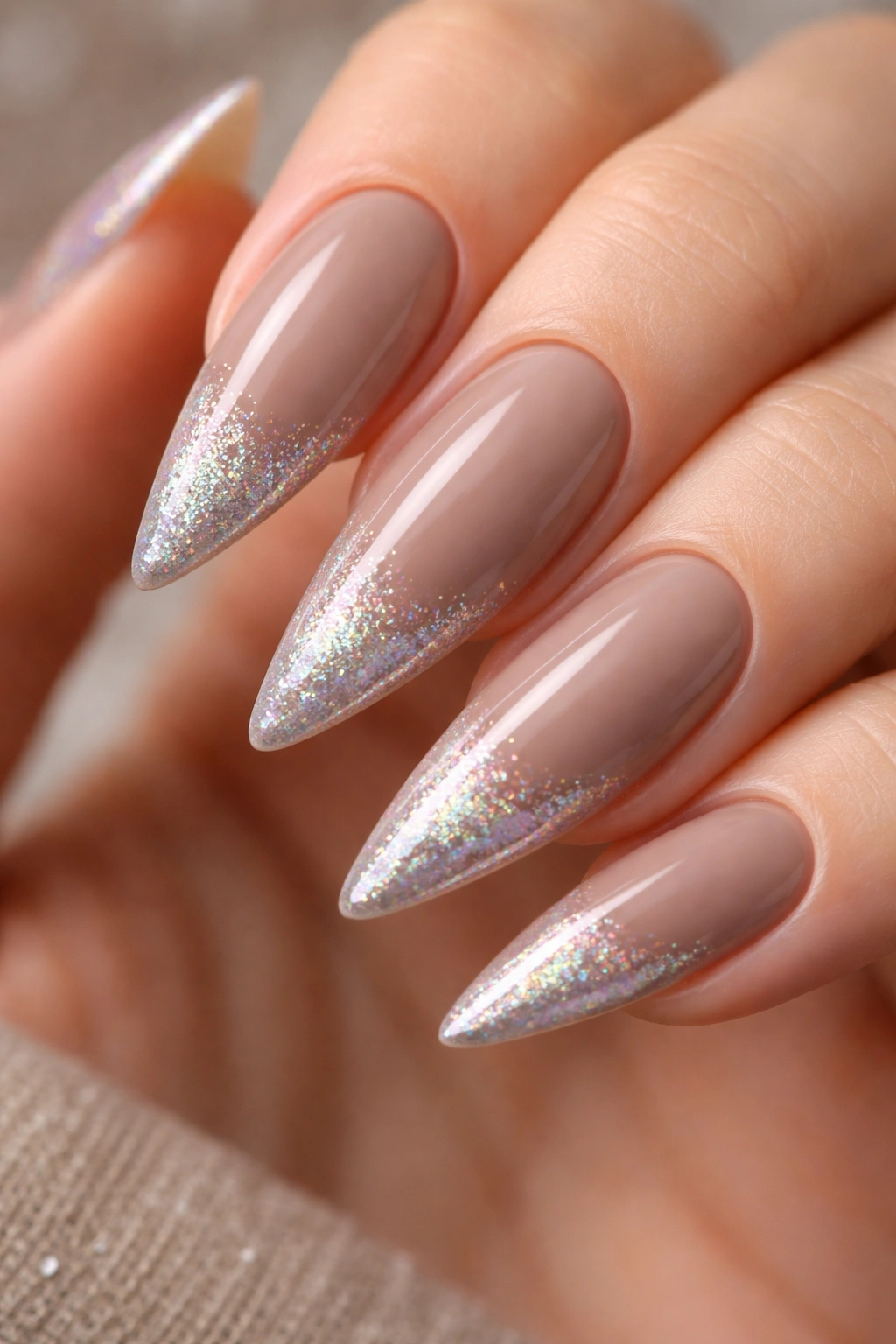 Close-up of taupe stiletto nails with holographic sparkle accent