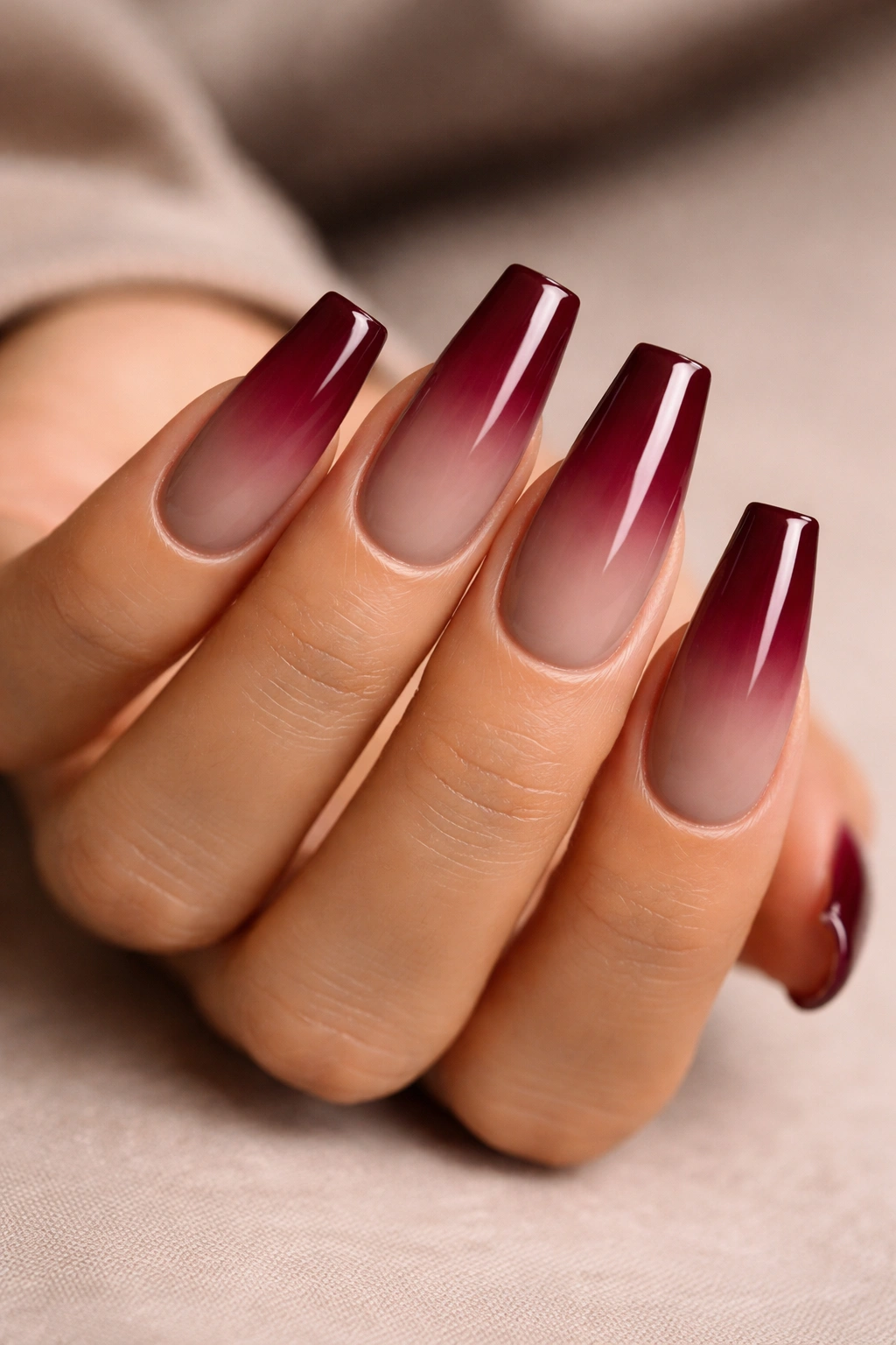Close-up of warm taupe coffin nails with burgundy ombre gradient