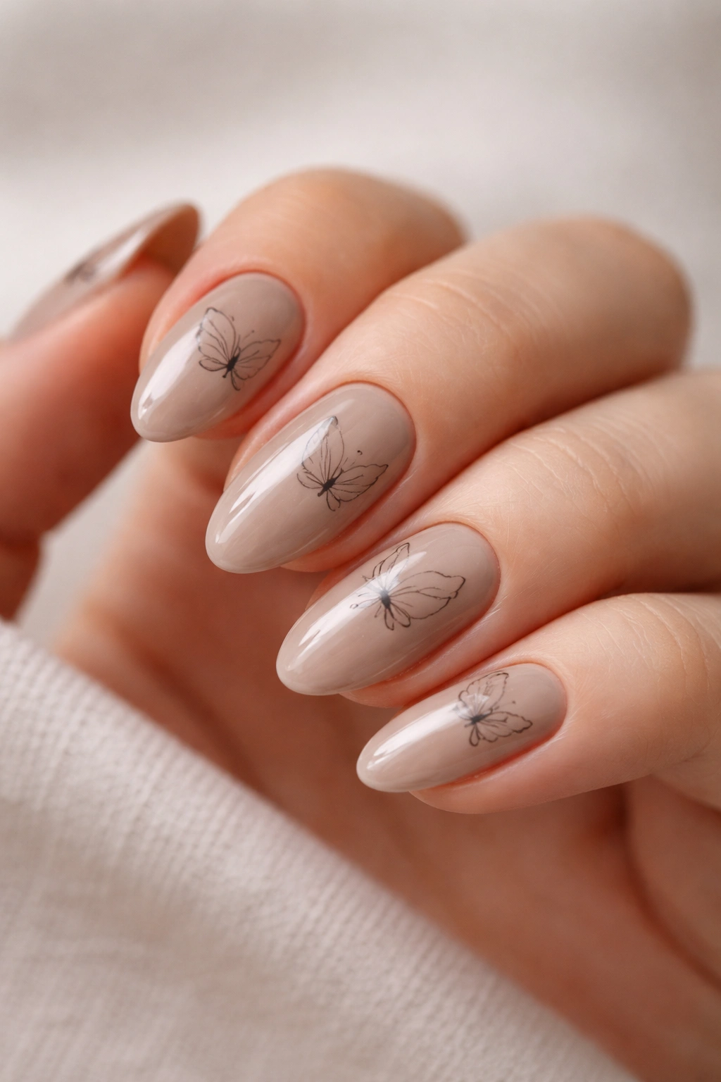 Taupe nails with minimal butterfly sketch art and glossy finish