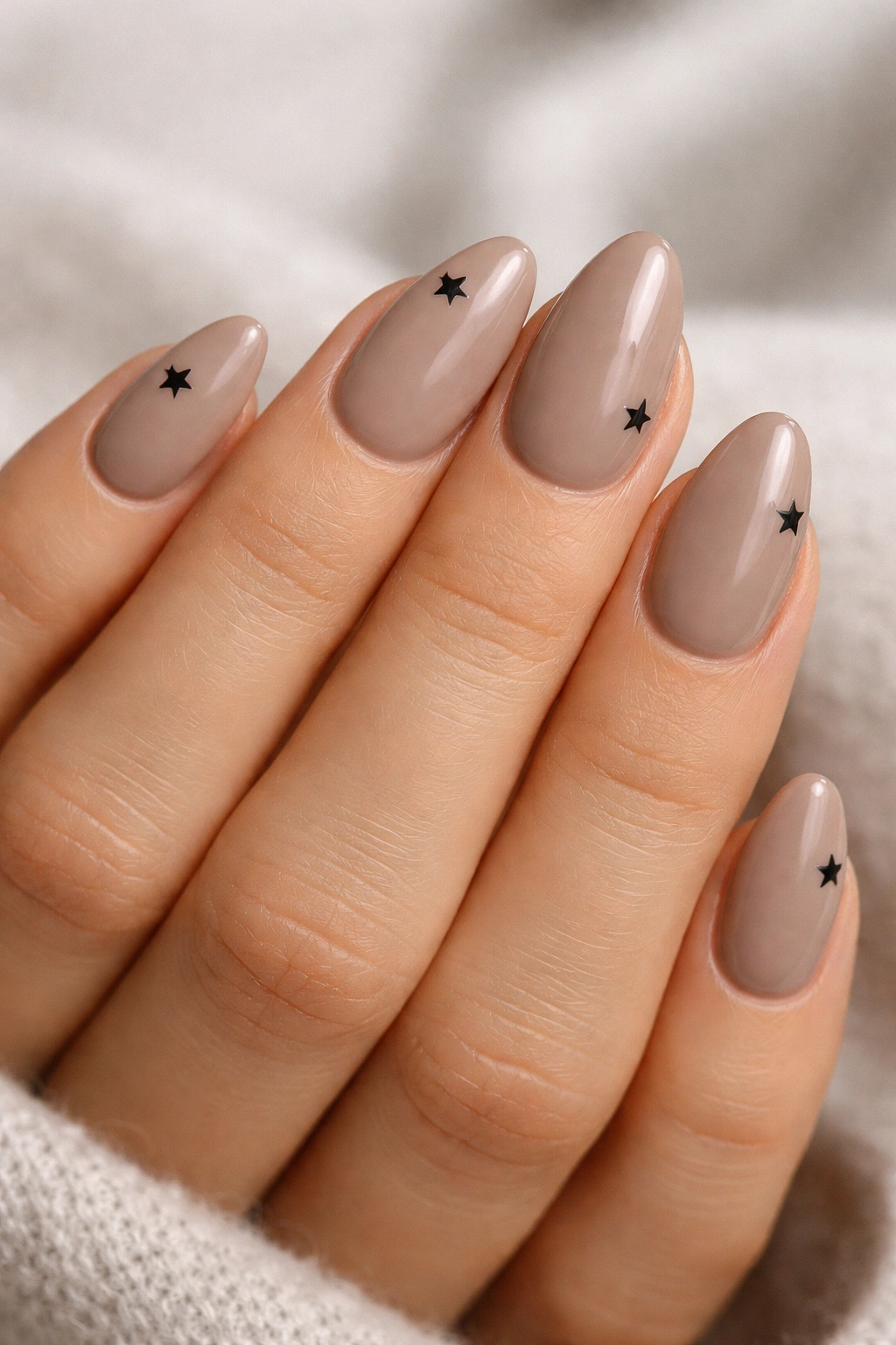 Taupe almond nails with minimalist black star corners