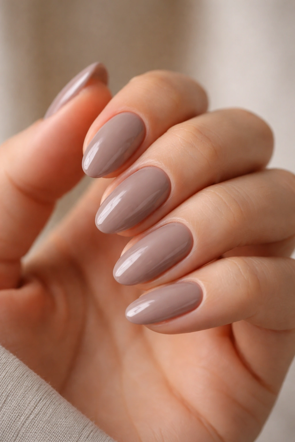 Close-up of glossy taupe almond nails on a hand