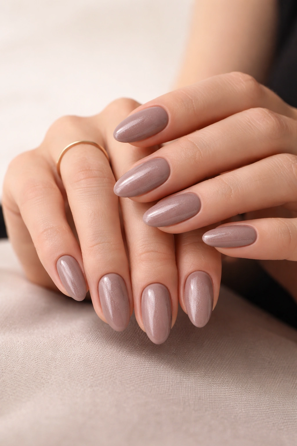 Close-up of taupe nails with subtle shimmer on hands in a minimalist studio