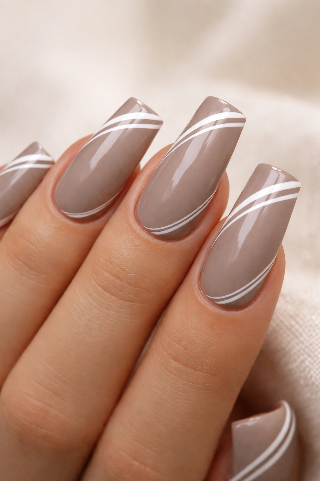 Close-up of warm taupe nails with white stripes on medium duck nails