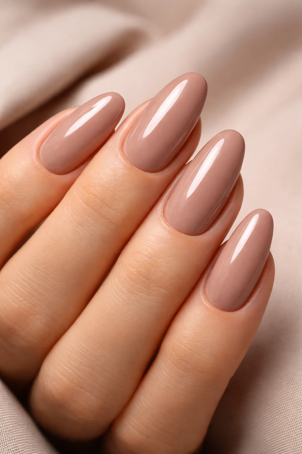 Taupe-nude oval nails with glossy finish reflecting light
