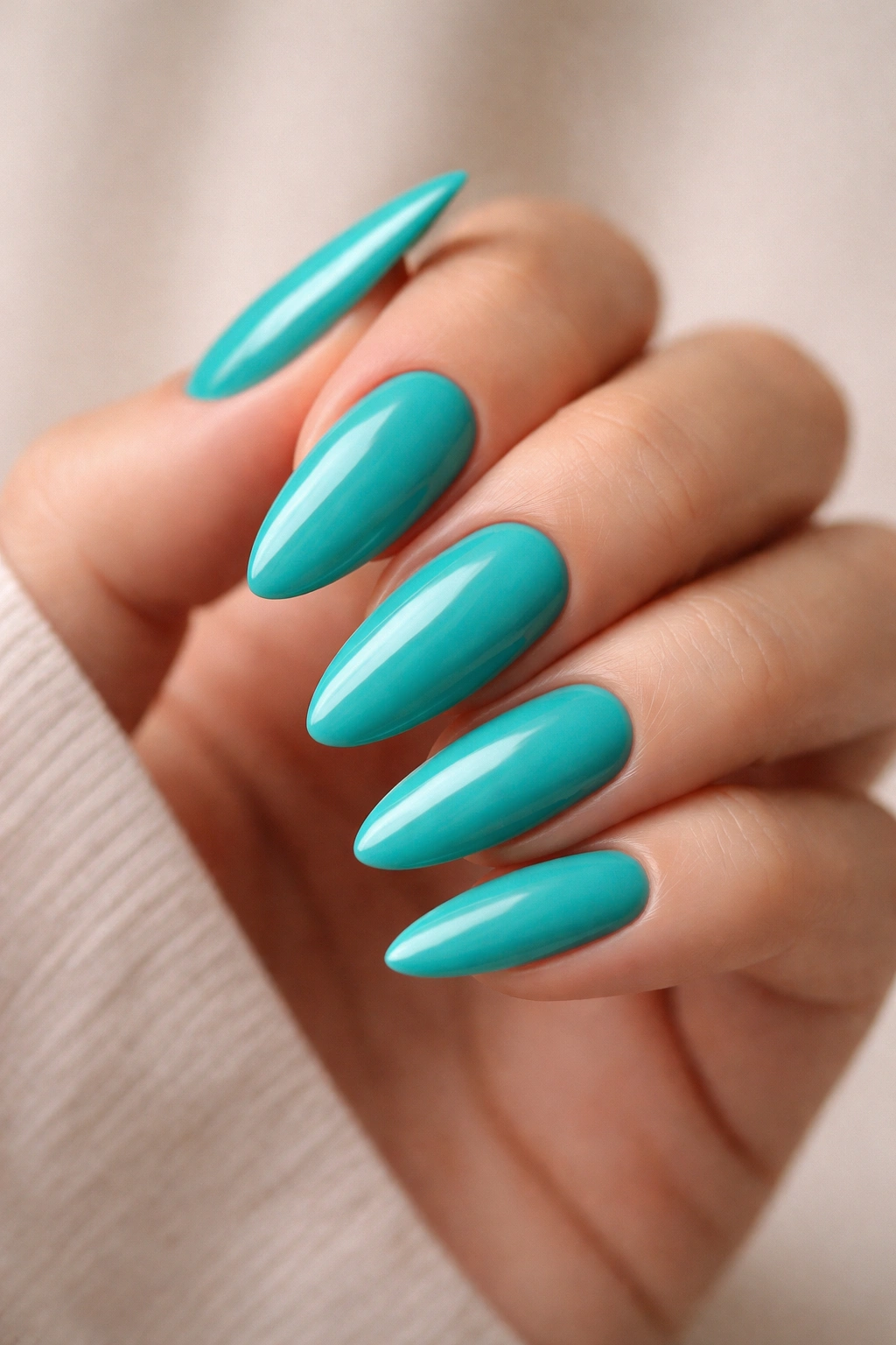 Close-up of teal almond nails with flawless, even color on a hand.
