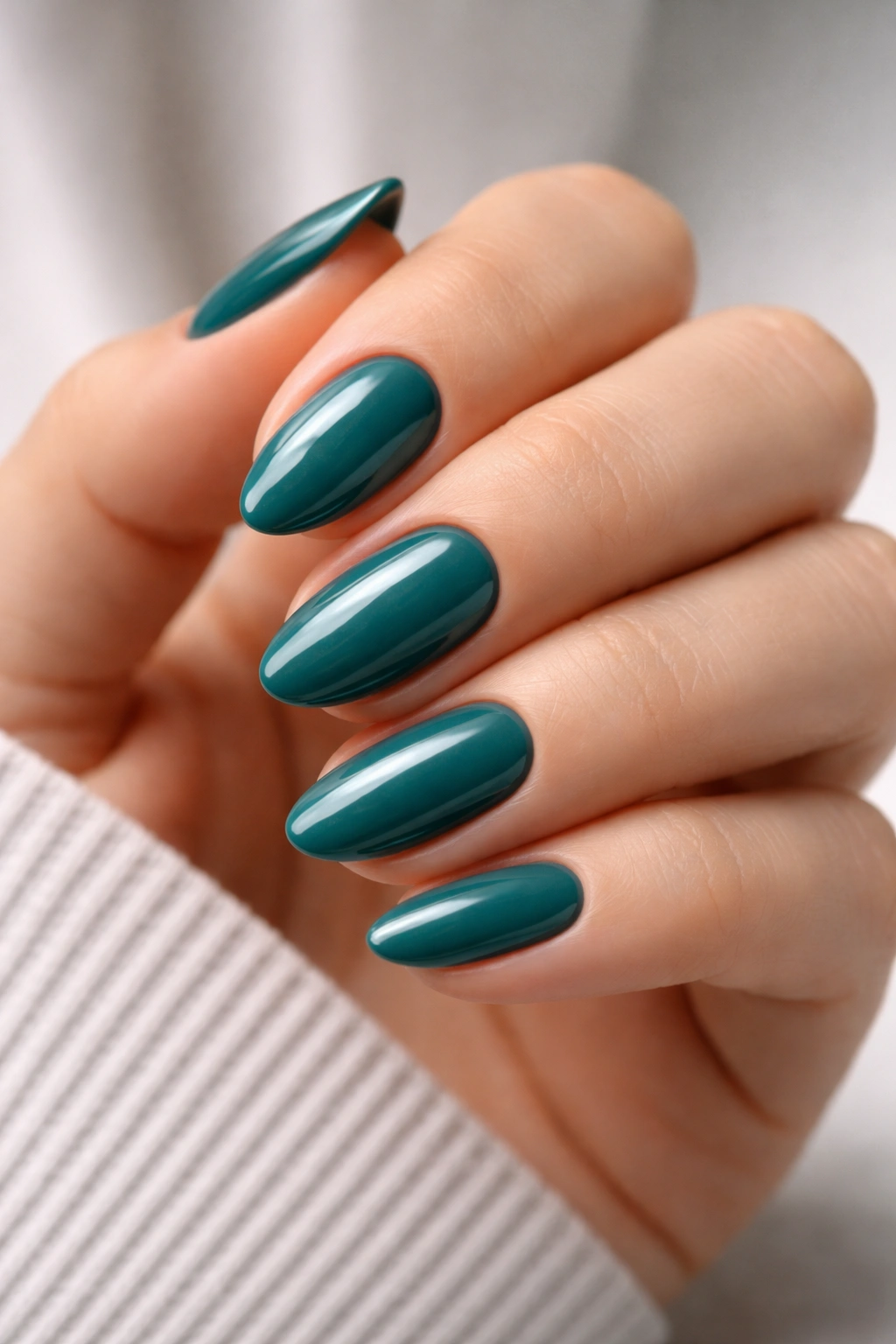 Close-up of short almond nails in teal glossy polish