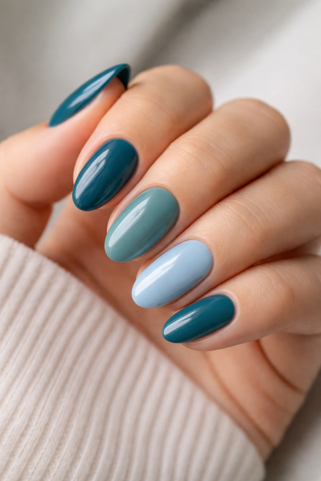Short almond nails in teal-blue color mix across the hand