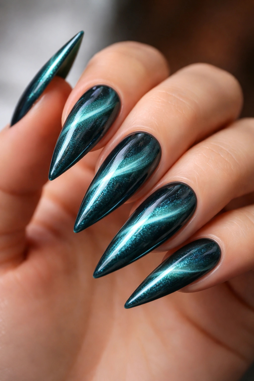 Close-up of teal cat eye nails with magnetic stripe on stiletto tips