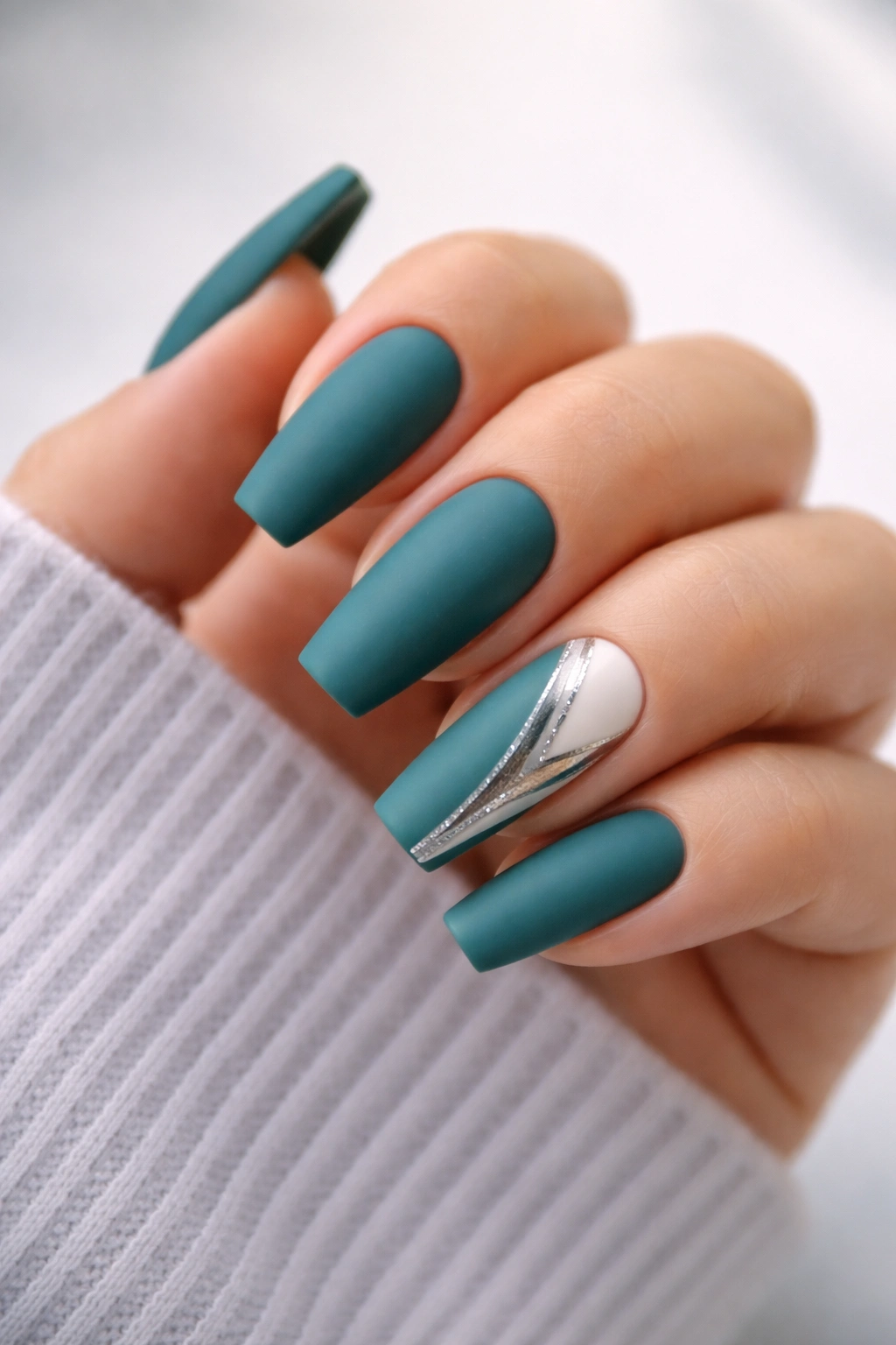 Close-up of teal matte coffin nails with accent nails featuring metallic highlights