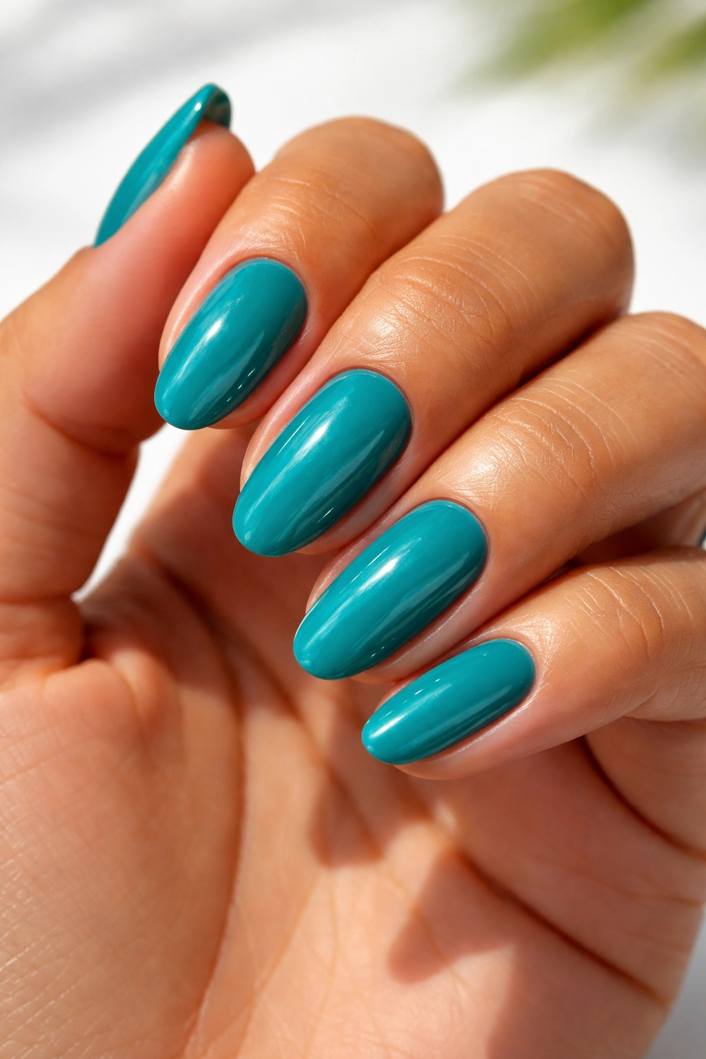 Close-up of teal nails on olive skin.