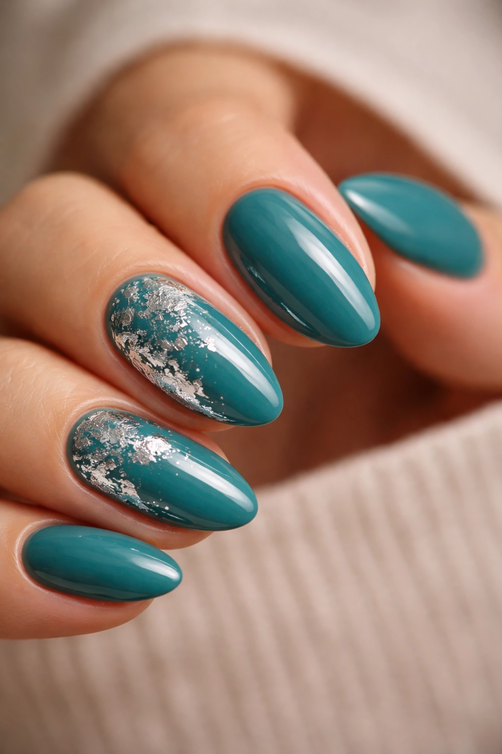 Close-up of teal nails with silver foil accents on short almond nails