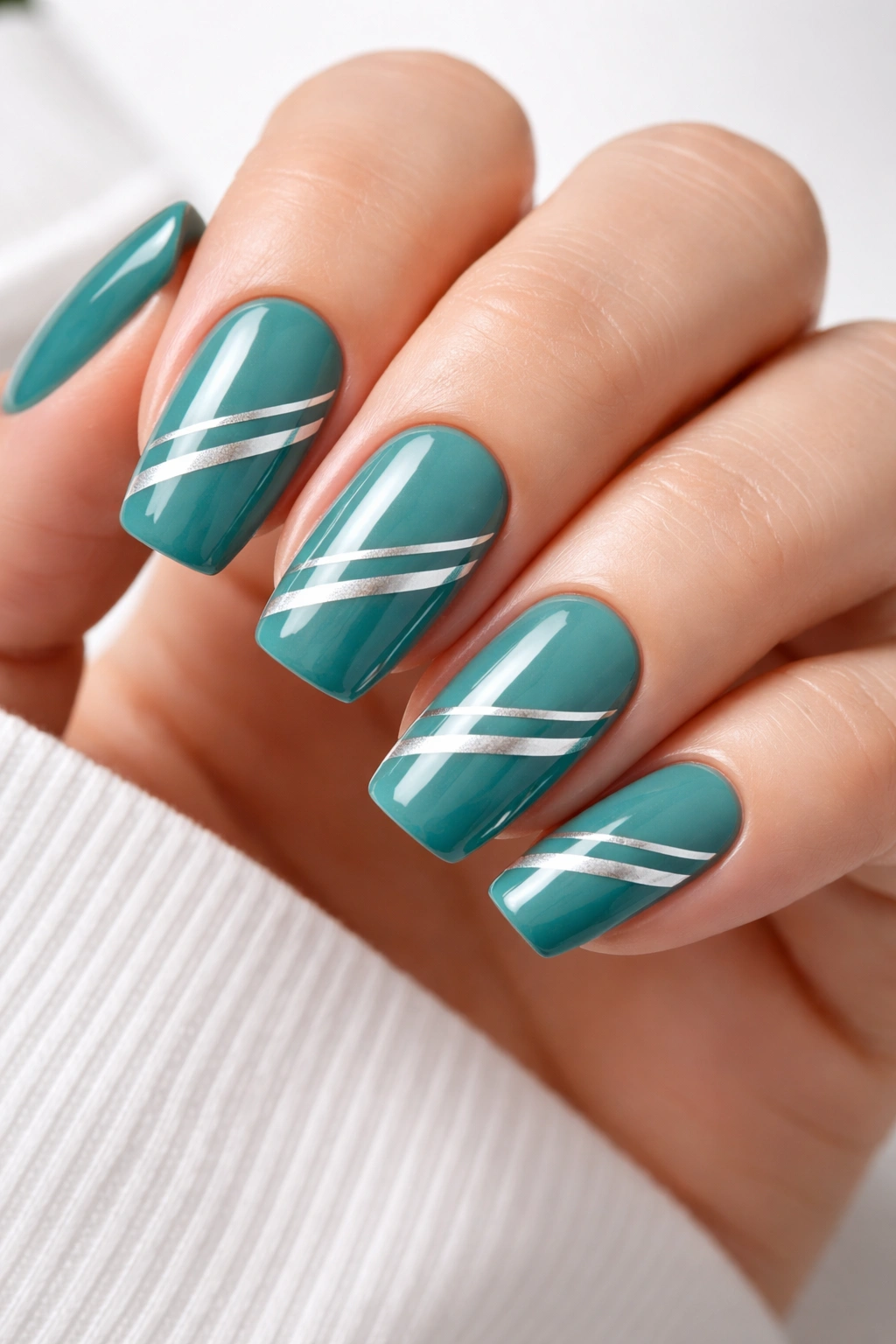 Teal nails with silver stripes in a modern striped design