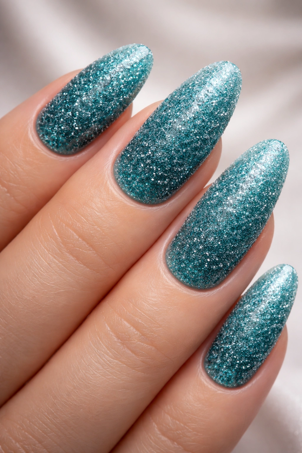 Close-up of teal sugar nails on long round nails with crystalline texture