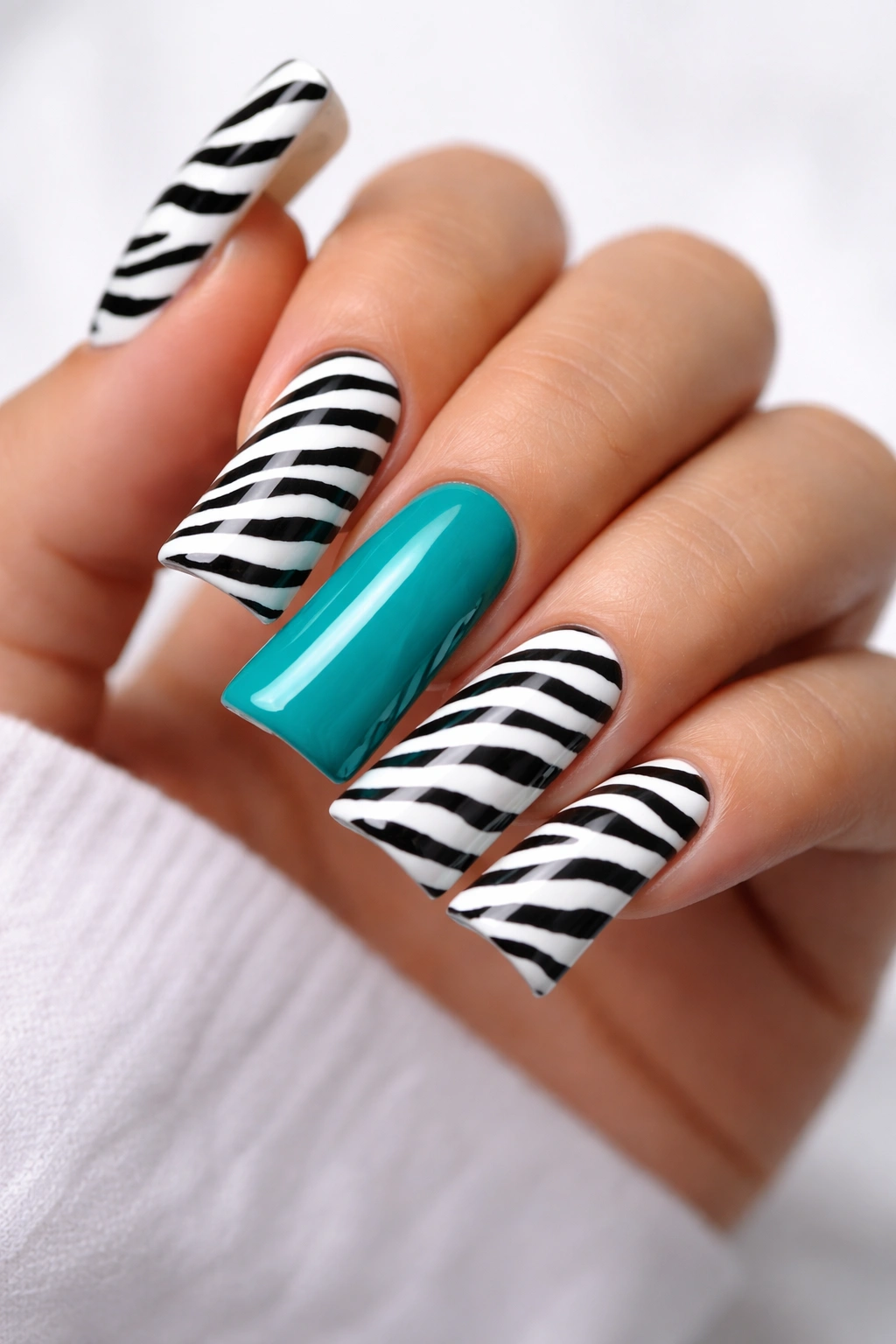Duck nails with black-and-white zebra stripes and a teal accent nail