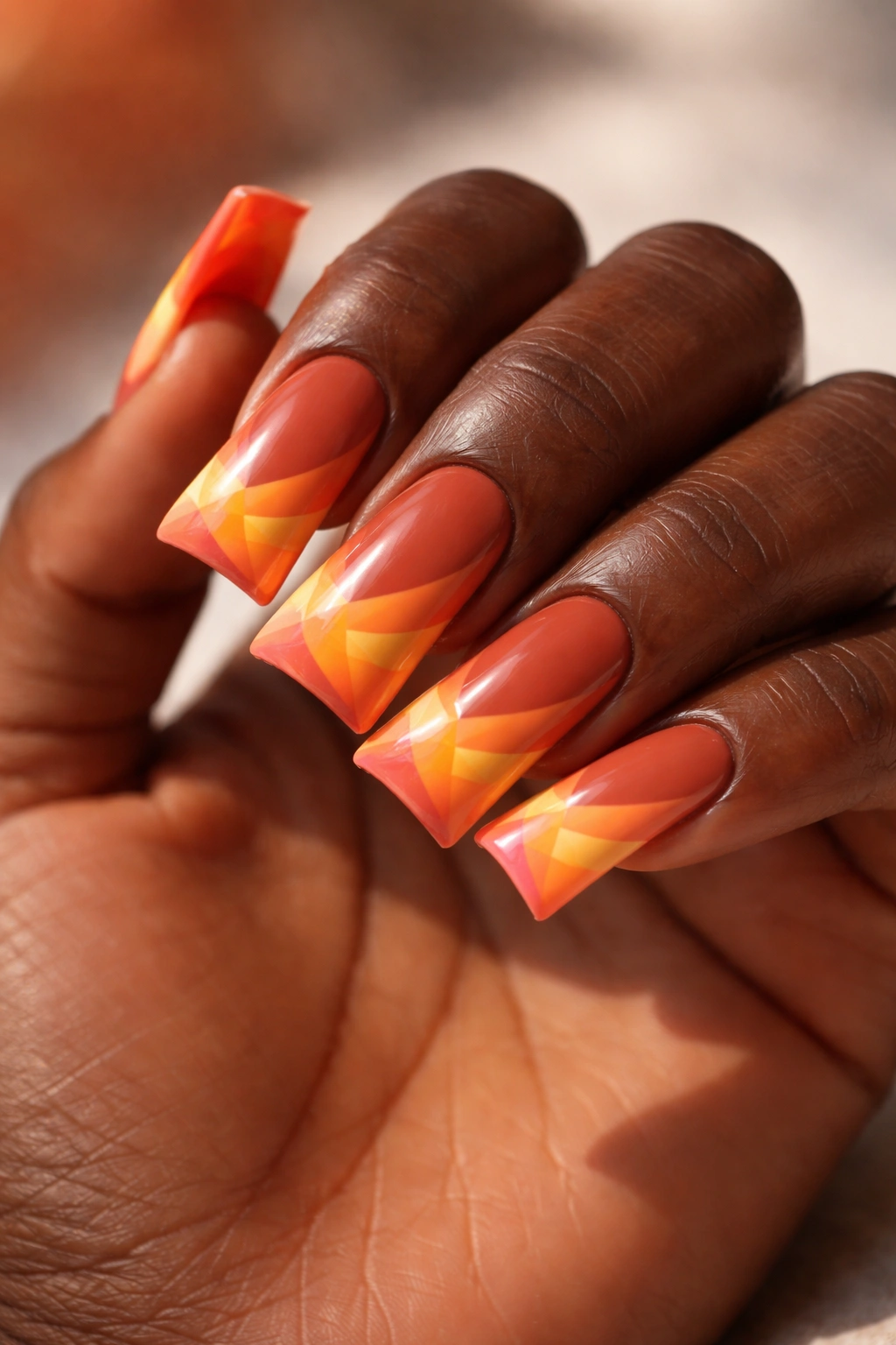 Terracotta duck nails with geometric sunset gradient on dark skin
