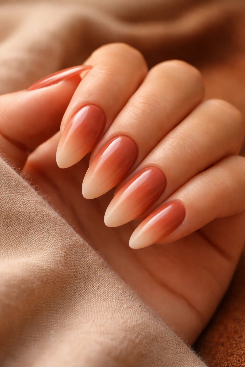 Macro shot of almond nails gradient from terracotta to sand on a neutral background