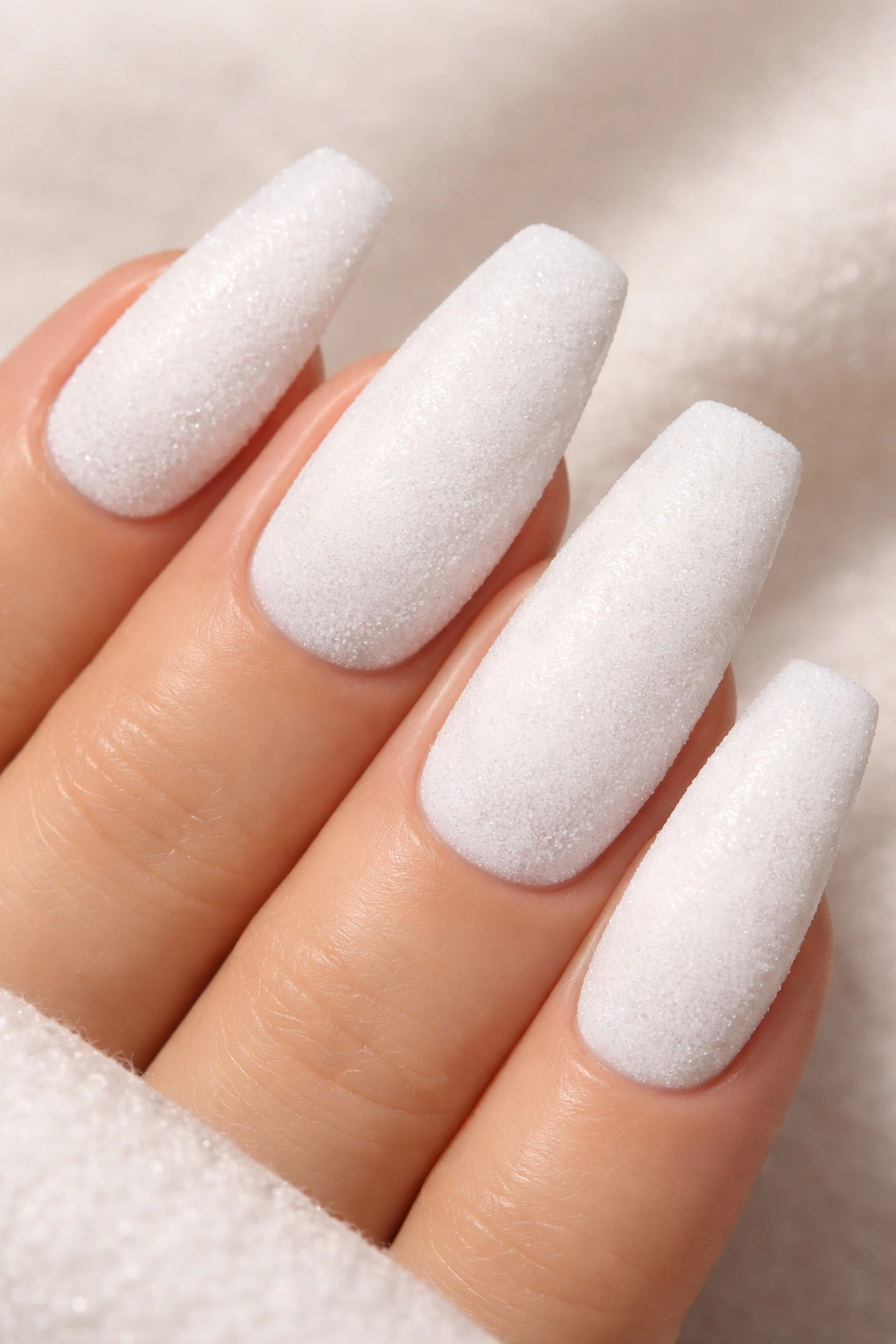 Close-up of coffin nails with a soft velvet texture on white polish