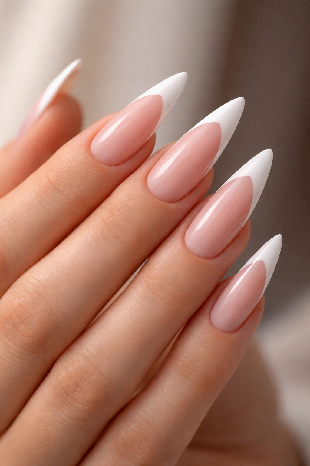 Close-up of stiletto nails with thick white tips on pink base