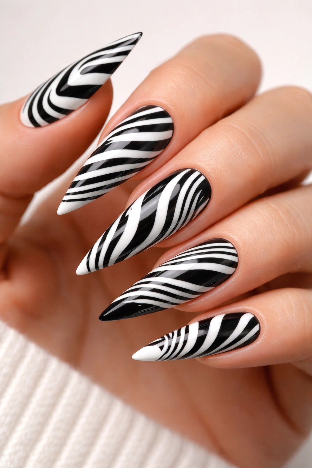 Close-up of stiletto nails with bold thick and thin black-and-white zebra stripes
