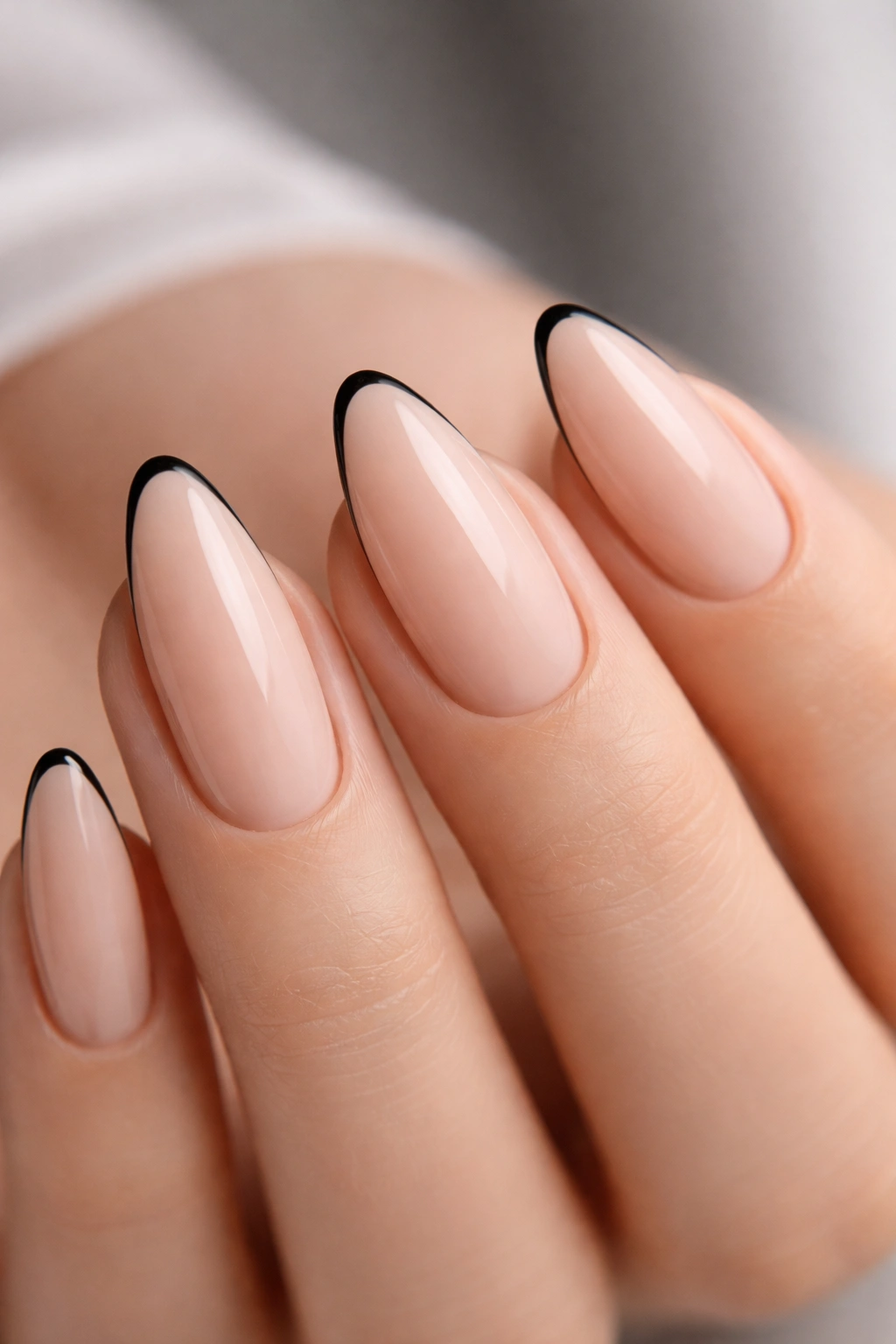Almond nail with a thin black tip on nude base