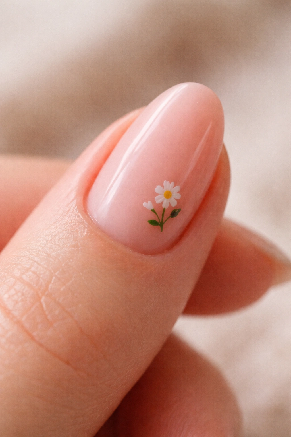 Close-up of a short almond nail with a tiny hand-painted floral detail on a sheer pink builder gel base