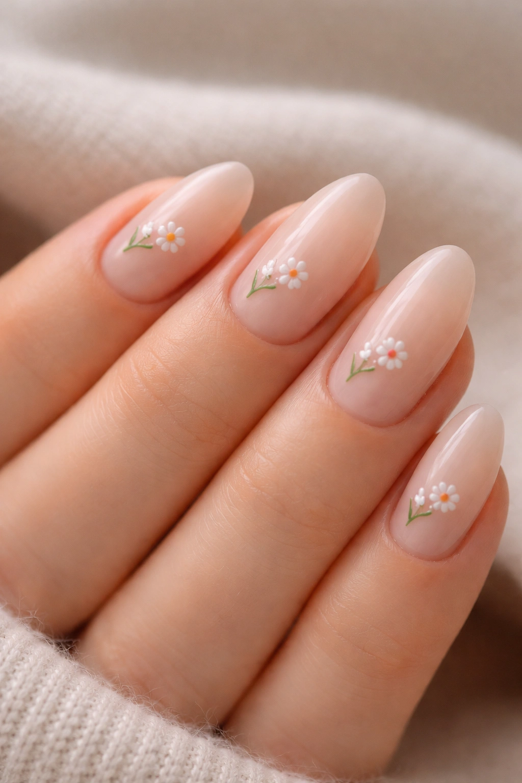 Close-up of almond nails with tiny floral art on nude base