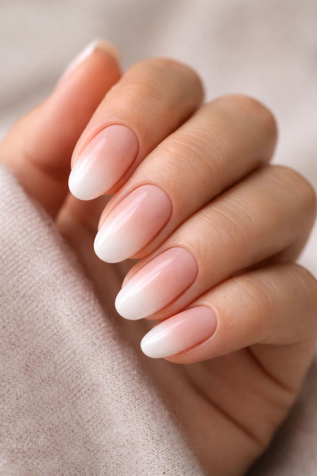 Close-up of tiny ombré dip nails on short almonds from nude to white