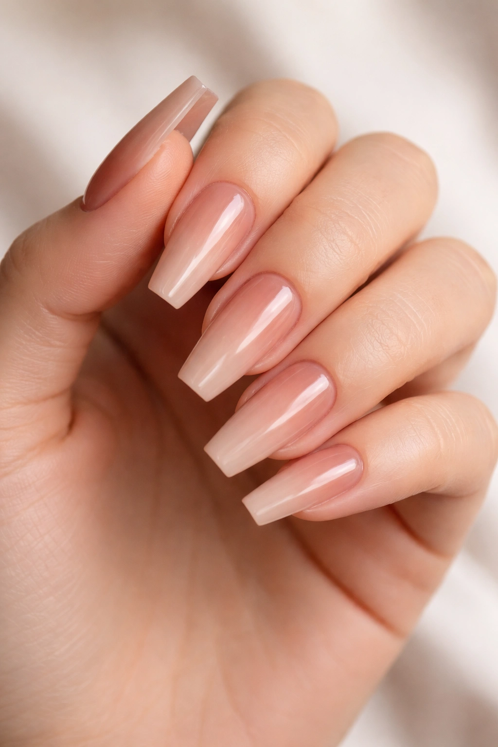 Close-up of hand with toffee nude nails featuring a soft ombré cuticle.