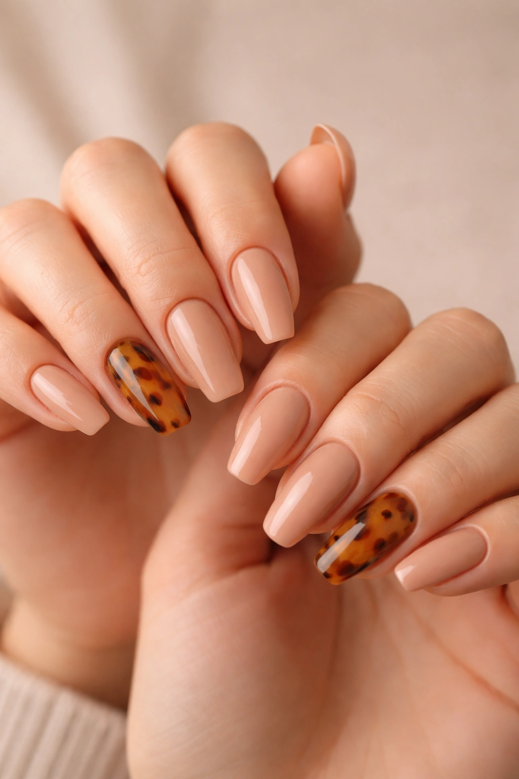 Close-up of medium-length ballerina nails in toffee nude with a tortoiseshell accent on one finger per hand
