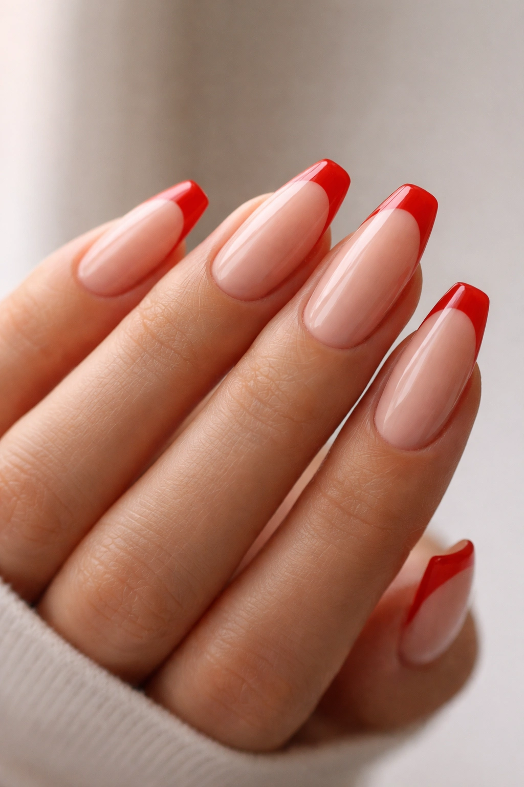 Hand with tomato red micro-French ballerina nails on nude base