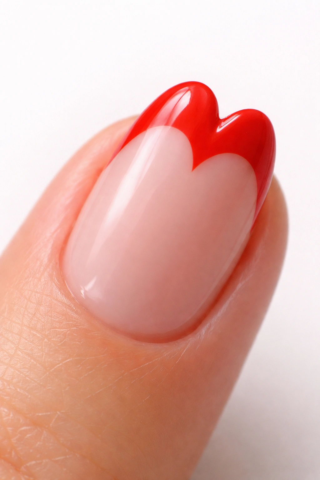 Close-up of a short almond nail with a tomato red heart-shaped tip on a neutral background